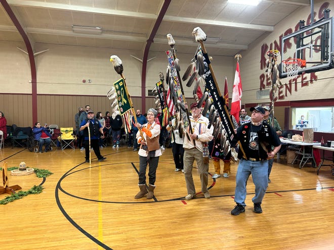 A veterans color guard stands indoors with American flags.